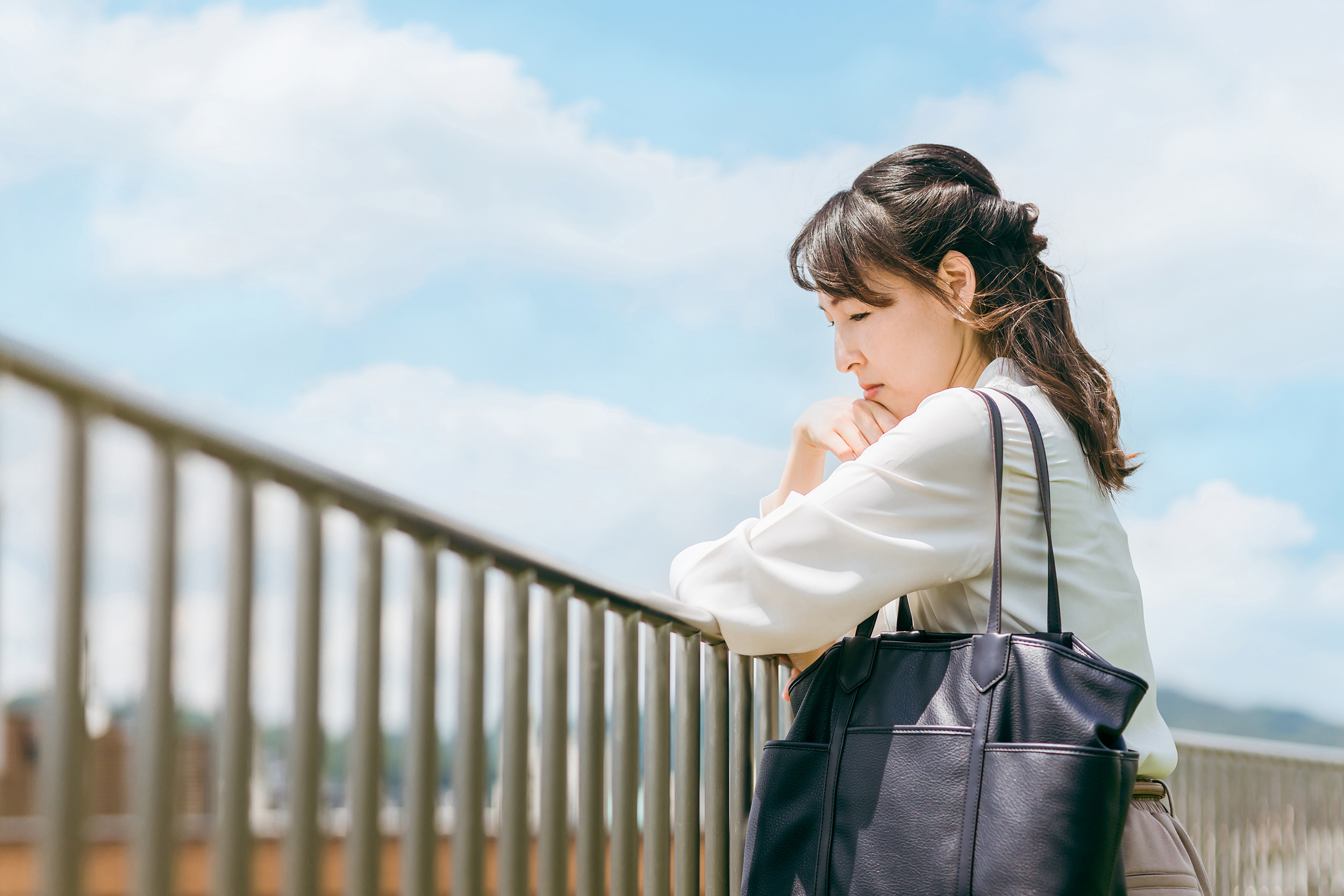 柵に手をついて悩む女性